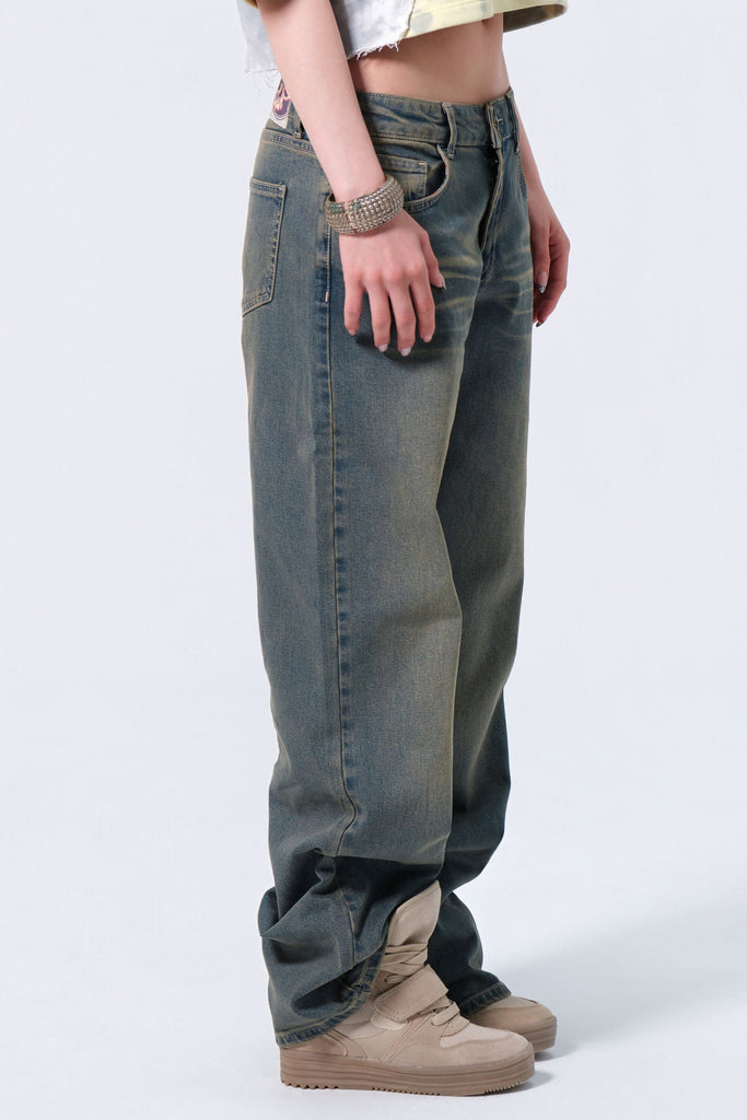 Person wearing a patterned crop top and high-waisted jeans on a white background