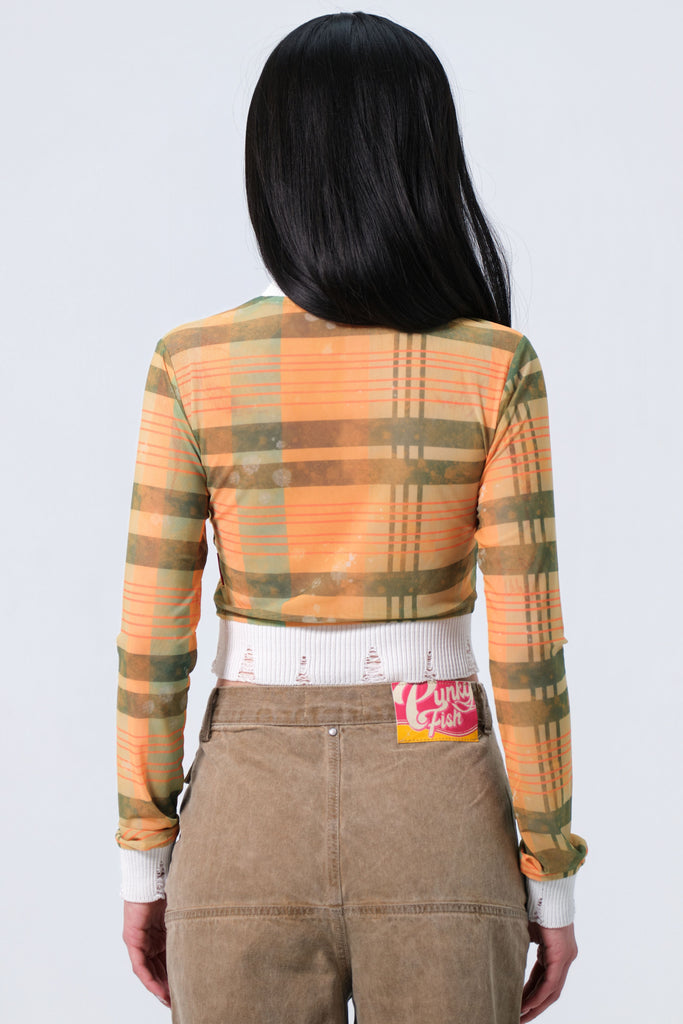 Person wearing a plaid shirt and brown pants with a visible brand label on a white background